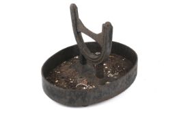 A 19th century cast iron boot scraper. Of horseshoe-shape on an oval tray base.
