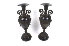 A pair of Victorian cast metal decorative urns. Set on turned black marble plinths.