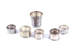 Five various silver and plated napkin rings and a French engraved beaker, approx. 150g.
