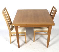 A contemporary extendable dining table and two chairs. The table raised on tapered supports, H76.