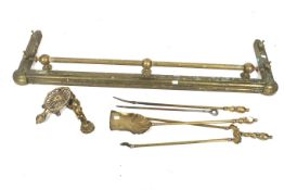 A Victorian brass fender and companion set.