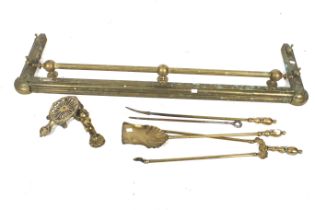 A Victorian brass fender and companion set.
