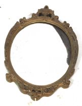 A gilt framed mirror. Of oval form, the frame featuring scrolling motifs, H72.5cm x W46.