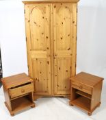 A contemporary pine wardrobe and pair of bedside cabinets.