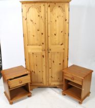 A contemporary pine wardrobe and pair of bedside cabinets.