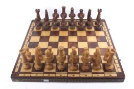 A large carved wooden chess set and matching folding board.