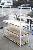 An industrial five tier white painted metal framed shelf unit. With three wooden shelves.