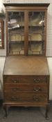 An early 20th century wooden bureau fitted with a display cabinet above.