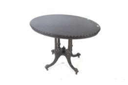 An oval ebonised centre-table.