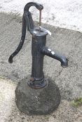 A vintage cast iron water pump and a carved serpentine stone plinth.