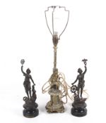 A pair of 19th century style statues and a brass lamp.