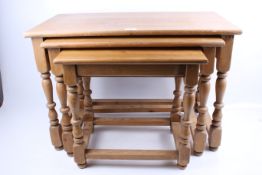A 20th century pine nest of three tables. All with turned supports united by stretchers, H50.