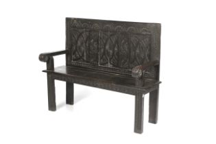 A Victorian carved and ebonised pine panel back settle or bench with open arms. H105.