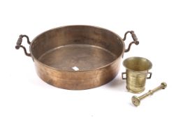 A 19th century copper twin handle pan and a brass pestle and mortar.
