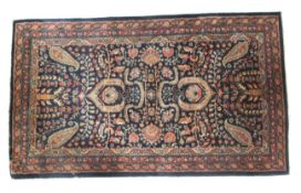 A dark blue ground rug with paisley decoration in blue and beige.