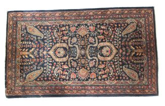 A dark blue ground rug with paisley decoration in blue and beige.