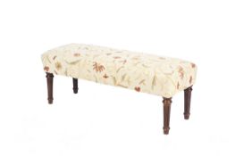A contemporary upholstered long stool with fluted and turned legs.