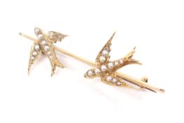 An early 20th century gold and half-pearl brooch in the form of two swallows.