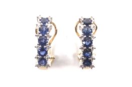 A pair of modern sapphire and diamond half-hoop earrings.