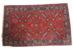 A deep red ground rug with geometric floral motifs in blues and greens.
