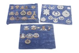 A collection of 35 assorted military cap badges mounted on three sheets.