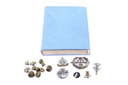A small group of military cap badges, buttons and an aviation book.