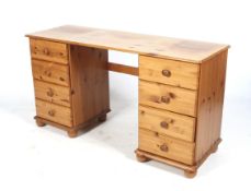 A contemporary pine twin pedestal dressing table. Two banks of four drawers, raised on bun feet.