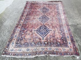 A handmade woollen rug with a light red ground.