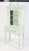 A contemporary French style green painted display cabinet on a stand.