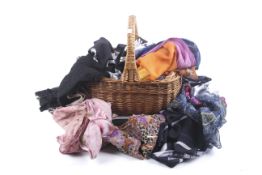 A wicker shopping basket full of assorted women's fashion scarves and gloves.