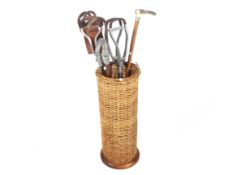 A collection of assorted shooting sticks, canes and a wicker umbrella stand.