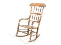 A late 19th/early 20th century elm rocking chair. With spindle back, turned uprights and cane seat.