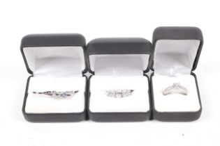 A shaped wedding-type band and three white stone or cubic zirconia rings.