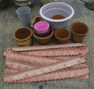 A group of assorted terracotta and plastic garden pots plus plastic lawn edging border sections.
