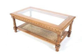 A vintage glass top coffee table. With a lower wicker work shelf, fluted column supports.