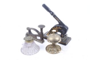 Four Edwardian desk office items. Comprising a desk bell, inkwell and two embossing stamps, Max.