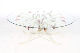 A mid-century oval glass topped table with a floral metalwork frame.