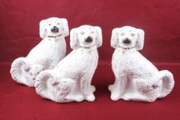 Three Staffordshire spaniels. All glazed in white with gilt details, H31.