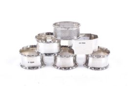 A set of four silver napkin rings and two others.