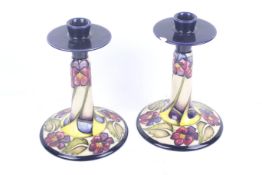A Moorcroft pair of candlesticks, 'The Dames, Pansy Pattern' Designer Kerry Goodwin, dated 2010.