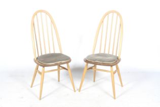 A pair of Ercol Windsor stick-back dining chairs with upholstered seat cushions.