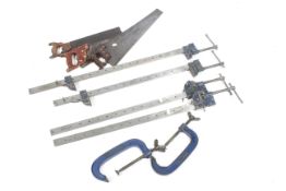 A collection of tools. Including four sash clamps, two G clamps and three saws.