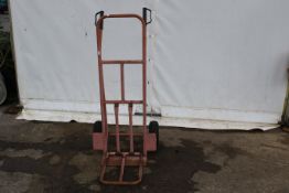 A set of metal sack trucks. Finished in pink with rubber tyres.