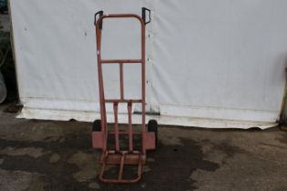 A set of metal sack trucks. Finished in pink with rubber tyres.