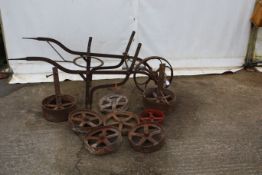 A collection of eight cast iron wheels plus a barrow.