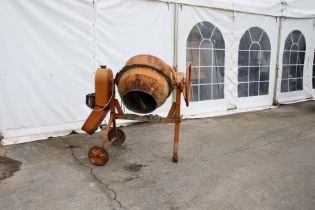 A vintage orange electric cement mixer. On a wheeled stand.