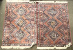 Two contemporary viscose rugs. With blue and beige geometric patterns on a red ground, with tassels.