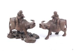 A pair of 20th century Chinese wood carvings of children seated on oxen.