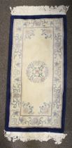 A contemporary Chinese style wool rug. Dark blue border, cream ground with floral decoration.