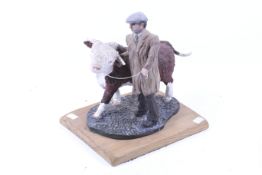A contemporary studio pottery sculpture of a farmer beside a bull.